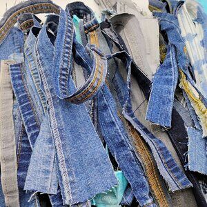 71 pieces of denim fabric scraps to include hems, seams, waistbands and zippers.